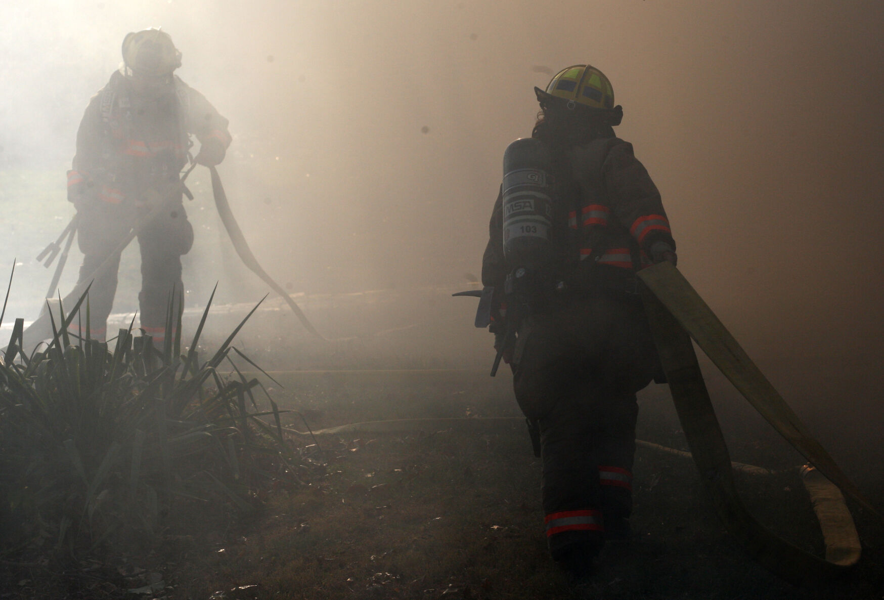 Firefighters walk through smoke